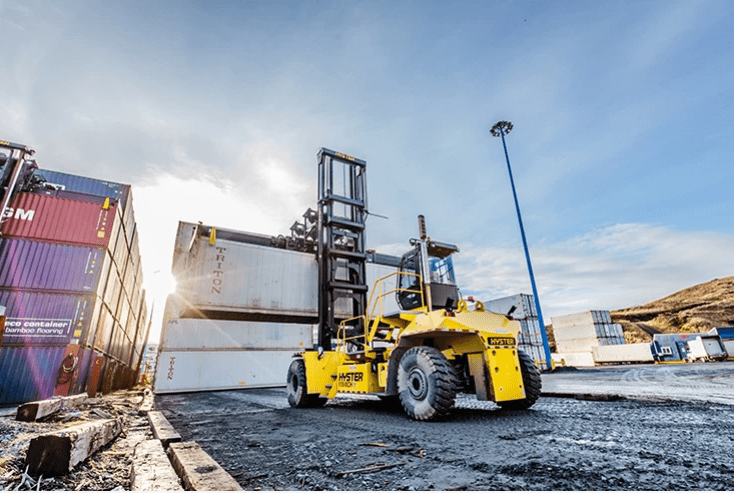 A yellow forklift is parked in the middle of an empty lot.