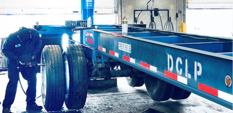 A blue truck with the trailer being worked on.